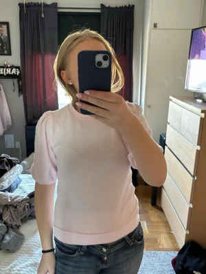 Ljusrosa topp med puffärm - Säljer en ljusrosa topp med korta puffärmar och rund hals. Toppen har en slim passform och är tillverkad i ett mjukt material som känns skönt mot huden. Perfekt för dig som gillar en enkel men söt stil.