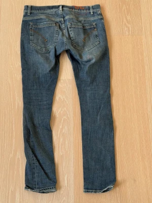 Blå skinny jeans från Dondup strl 29 - Snygga blå skinny fit jeans från Dondup med klassiska bakfickor och dragkedjedetaljer. Jeansen har en smal passform och är tillverkade i ett mjukt denimtyg som sitter tajt längs benen. Perfekta för en trendig och avslappnad look.