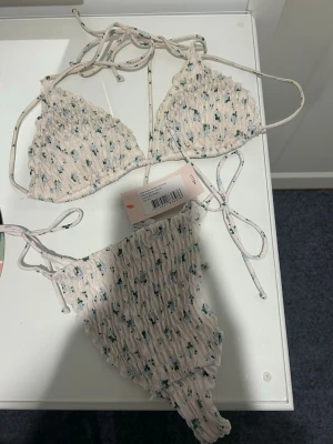Blommig bikini från Nelly med snörning - Supersöt bikini från Nelly imed små blommor. Har aldrig använt underdel och den har lappen kavr! Har använt överdelen fåtal gånger! Storlek M i bh och storlek XS i trosorna!❤️❤️