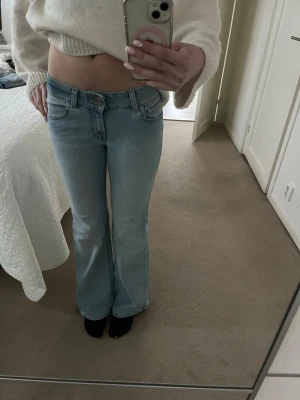 Ljusblå bootcut jeans från Levi's - Säljer ett par ljusblå bootcut jeans från Levi's med klassisk femficksdesign och låg midja. Jeansen har Levi's ikoniska läderpatch bak och är tillverkade i denim med lätt tvättad look. Perfekta för en avslappnad och trendig stil.