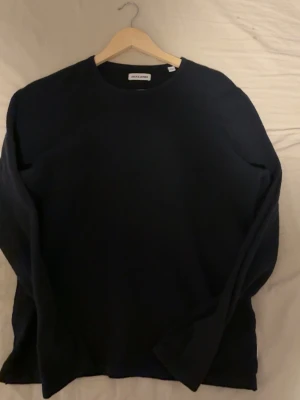 Mörkblå stickad tröja Jack & Jones - En enkel och stilren mörkblå stickad tröja från Jack & Jones. Tröjan har rund halsringning och långa ärmar. Perfekt basplagg till garderoben och lätt att matcha med olika outfits.