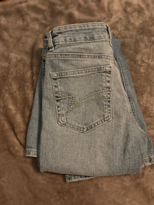 Ljusblå jeans från Junkyard XS - Säljer ett par ljusblå jeans från Junkyard i storlek XS. Klassisk femficksmodell med cool kontrastsöm på bakfickan. Jeansen har bra passform och är utsvängda i benen 