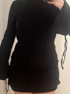 Långärmad kort klänning - Svart kortklänning från Monki med lång ärm och snörningsdetaljer vid ärmsluten. Knappt använd men supersnygg🩷🩷