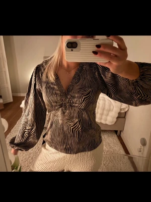 Zebramönstrad blus med v-ringning - Snygg blus med zebramönster i svart och beige, v-ringad och med långa puffiga ärmar. ordinariepris rint 800kr helt slutsåld! (Har lite defekter som man ser på nära håll) 🤍🖤🦓