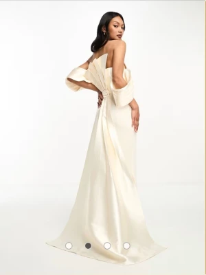 Elegant off-shoulder långklänning balklänning bröllop - Säljer en lyxig, ljusbeige långklänning från Nadine Merabi med off-shoulder design och dramatiska ärmar. Klänningen har en figurnära passform och är tillverkad i glansigt satinliknande material som ger en exklusiv look. Perfekt för dig som vill sticka ut.