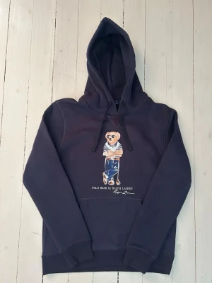 Ralph Lauren polo bear hoodie herr, storlek S - Hej! Säljer denna riktigt schyssta polo bear hoodie från Ralph Lauren. Den är i storlek M men sitter en storlek litet och passar därför som en S. Den är endast använd någon enstaka gång och är därmed i ett nyskick. Original lappar och påse finns kvar och medföljer naturligtvis vid köp. Jag fraktar alltid snabbt!  Mvh
