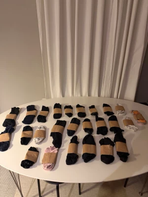 Stort paket med blandade strumpor - Säljer ett paket med flera par strumpor i olika färger och modeller. Mest svarta, men även vita, blå, lila, rosa och ett par med orange text. Perfekt för dig som vill fylla på strumplådan snabbt. De flesta är i bomull och syntetblandning.