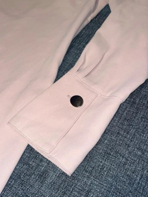 Ljusrosa klänning med v-ringning - Enkel ljusrosa klänning med v-ringad hals och långa ärmar. Klänningen har fina knappar och en lite mer rak passform. Perfekt för dig som gillar stilrena och feminina plagg 🩷