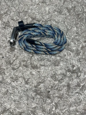 Blått flätat bälte med silverdetalj - Snyggt flätat bälte i blå och grå toner med silverfärgat spänne. Bältet har en smal design och är gjort i ett mjukt syntetmaterial. Perfekt för att göra din outfit snyggare 