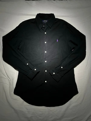 Ralph Lauren skjorta  - En riktigt schysst skjorta ifrån Ralph Lauren, skjortan är i slim fit storlek M men passar även om man vill ha de lite lösare! Den enda skavanken jag upptäckt är ett pyttelitet hål som kan ses på den bild lappen visas, men utöver det är den i ett mycket fint skick och har mycket mer att ge! 👌 Tveka inte på att skriva ifall du är i behov av fler bilder på plagget eller mått! 📸📏 Skriv vid minsta lilla fundering då jag oftast svarar fort! 💬 Fraktar alltid samma dag eller dagen efter beställning! 🚛