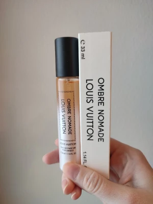 Louis Vuitton Ombre Nomade - Lyxig parfym från Louis Vuitton, Ombre Nomade, i en smidig cylinderformad glasflaska med svart lock. Flaskan rymmer 33 ml och har en stilren vit etikett med svart text. Kommer i originalförpackning.