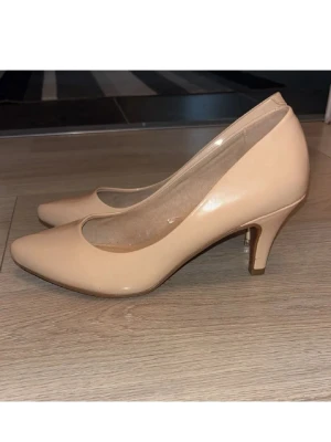 Beiga klackskor  - Snygga beige klack från Alley i storlek 37. Skorna har spetsig tå och är tillverkade i syntetmaterial med en slät finish. Perfekta för dig som gillar stilrena och klassiska klackar med modern touch.