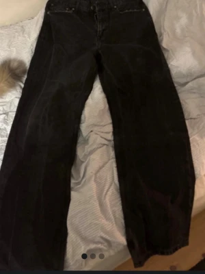 Svarta vida jeans med raka ben - Säljer ett par svarta jeans med raka, vida ben och klassisk femficksmodell. Jeansen har hög midja och är tillverkade i denim. Perfekta för en avslappnad och trendig look.