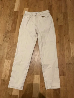 Beiga raka jeans - Snygga raka jeans i beige färg med klassisk femficksdesign. Jeansen har hög midja och raka ben, perfekta för en clean och stilren look. Materialet är kraftigt och känns som bomullsdenim. Passar till allt och ger en fräsch vibe.