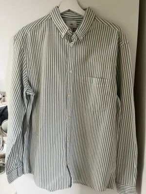 Randig skjorta från H&M i bomull - Snygg skjorta från H&M med vita och gröna vertikala ränder. 