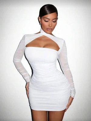 Vit tight kortklänning med mesh - Säljer en vit kortklänning med långärmade meshärmar och snygg cut-out vid bröstet. Klänningen är figurnära och har rynkade detaljer som framhäver siluetten. Perfekt för dig som vill sticka ut med en modern och trendig look. Tog en bild från hemsida! Aldrig kommit till användning