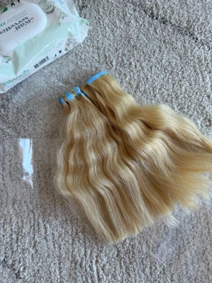 Blonda vågiga löshår extensions - Säljer blonda vågiga löshår extensions med tejpfästen. Färgen är ljusblond och håret har en naturlig glans och mjuk känsla. Perfekt för dig som vill ha längre eller fylligare hår på ett smidigt sätt. Materialet är äkta hår.