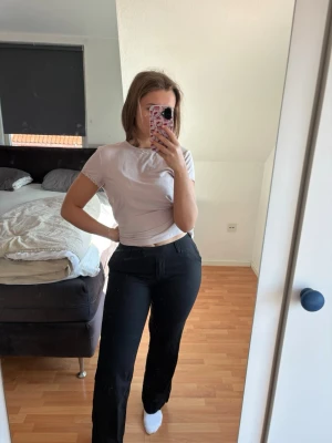 Svarta kostymbyxor i linnemix - Säljer ett par svarta kostymbyxor med rak passform och hög midja. Byxorn har klassiska fickor fram och bak och är tillverkade i ett material som sitter snyggt. Perfekta för dig som vill ha en stilren och enkel look. Helt felfria! Nypris 500kr