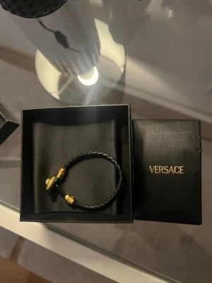 Svart flätat armband från Versace - Stilrent svart armband från Versace med flätad läderrem, säljer då jag köpte till min sambo men den var lite för stor🩷aldrig andvänt, kommer med box..