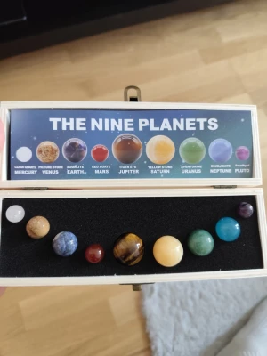 Planetset i ädelstenar med trälåda - Snyggt set med solsystemets nio planeter, där varje planet är en polerad sten som representerar dess utseende. Kommer i en trälåda med svart skum och informativt kort om planeterna. Perfekt som dekoration eller present till rymdintresserade.