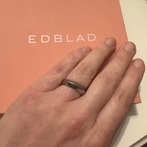 Edblad silverfärgad ring  - Stilren och modern ring från Edblad i silverfärgad metall. Ringen har en slät och blank yta med en lätt kantig form som ger en cool och minimalistisk vibe. Perfekt för dig som gillar enkla men snygga accessoarer. 