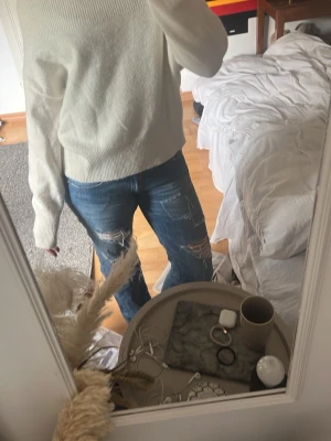 Vit stickad tröja med rund hals - Mysig vit stickad tröja med rund hals och långa ärmar. Tröjan har en avslappnad passform och ribbstickade muddar vid ärmslut och nederkant. Perfekt för lager-på-lager och enkel att matcha med jeans eller kjol.