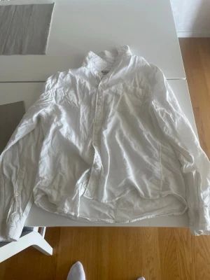 Dressman skjorta S - Säljer en vit långärmad skjorta i bomull i perfekt skick har använt den kanske 1-2 gånger. Skjortan har klassisk krage och knäppning framtill. Skjortan har en bröstficka och en avslappnad passform, perfekt till jeans eller chinos.