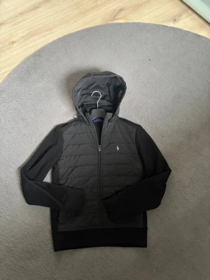 Svart Ralph Lauren Cardigan  - En skit snygg svart Ralph lauren cardigan originellt köpt för 3000. Perfekt för sommar kvällar eller blåsiga dagar. bara använd i någon månad eftersom den passade ej mig så bra i storlek xs. Denna cardigan är riktig komplimang fiskare eftersom den är stilren men ingen går runt med den👀, Storlek Xs, Nypris 3000, Äkta såklart. Först till Kvarn 🥇