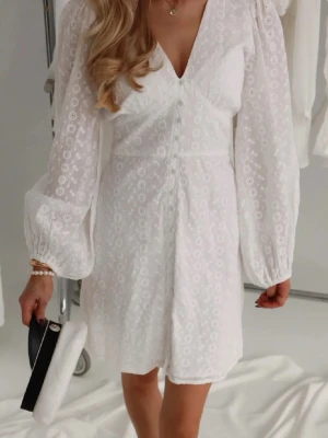 Populär studentklänning från Bubbleroom  - Superfin vit studentklänning från Bubbleroom med broderade detaljer och knappar framtill. Klänningen har v-ringning, långärmade puffärmar och markerad midja med smock baktill. Helt i nyskick med prislapp och orginalförpackning, säljer då den tyvärr inte passade mig. Nypris:699kr💗