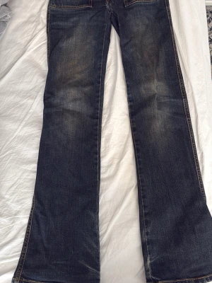 Mörkblå bootcut jeans - Mörkblå bootcut jeans från lager 157 med lätt tvättade detaljer. Klassisk femficksmodell och kontrastsömmar. Perfekta för en avslappnad och trendig look. De har ett hål i skrevet som lätt går att sy ihop + de är lite nötta vid fötterna. Säljer då de är för små. Storlek XS full length.