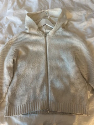 Vit stickad hoodie med dragkedja - Mysig stickad hoodie i Vit färg, den har en dubbel dragkedja så man kan välja hur mycket man vill dra upp både uppe och nere ifrån💛