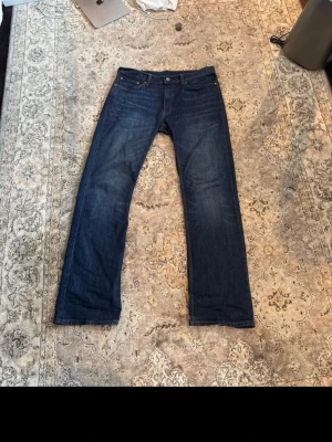 Levi's 527 mörkblå jeans bootcut - Säljer ett par klassiska populära Levi's 527 jeans i mörkblå denim med bootcut passform. Jeansen har fem fickor, gylf med dragkedja och snygga kontrastsömmar. Perfekta för dig som gillar tidlös stil och vill ha ett par jeans som funkar till det mesta.