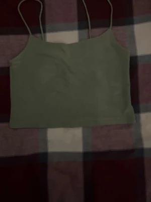 Ljusgrön croppad linnetopp - Snygg ljusgrön croppad linnetopp från New yorker med tunna axelband. Perfekt till sommaren och enkel att matcha med både jeans och kjol. Tillverkad i mjuk bomull för en bekväm känsla.