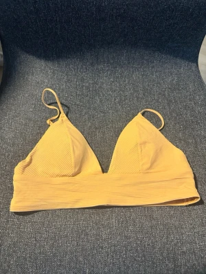 Orange ribbad bikiniöverdel - Trendig orange/peach bikiniöverdel med ribbad struktur och smala axelband. Enkel och stilren design som passar perfekt till sommaren. Bekväm passform och snygg färg som sticker ut på stranden.