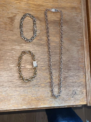 Kejsar kedjor  - Två chunky kedjearmband i guld- och silverfärg med rejäla länkar och dekorativa lås. Perfekta för att ge din outfit en edgy touch. Passar dig som gillar statement-smycken och vill sticka ut.