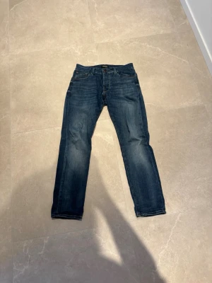 Mörkblå Jack&Jones jeans - Snygga mörkblå jeans med slim passform och klassisk femficksdesign. Jeansen har subtila slitningar och är tillverkade i ett mjukt denimtyg som ger en avslappnad look. Perfekta för dig som gillar en enkel och tidlös stil.