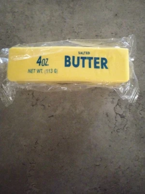 Salted butter squishy - Salted butter squishy i en rektangulär gul kloss.. Smöret är förpackat i transparent plast och har tydlig blå text på förpackningen. 