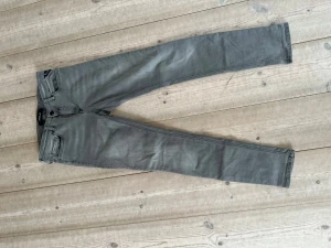 Grå slim fit jeans från Replay - Snygga grå slim fit jeans från Replay med klassisk femficksdesign och dragkedjegylf. Jeansen har smal passform och raka ben, perfekta för en stilren look. Materialet är mjukt och stretchigt för extra komfort. Storlek 29x30 replay hyperflex