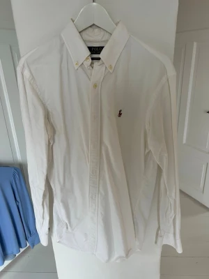 Skjorta ifrån Polo Ralph Lauren - Klassisk vit custom fit Oxford skjorta från Polo Ralph Lauren. Väldigt bra skick eftersom att den är använd ett fåtal par gånger! Nypris 1900kr 