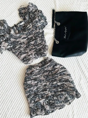 Zara tvådelat sommar-set  - Spanskt set med unikt tryck. Kjolen har en smickrande passform som framhäver figuren. Blusen har underbara fina ärmar som skapar wow-effekt.  Blus: Midja 35 cm,längd 40 cm Kjol: Midja 35 cm, längd 40 cm 