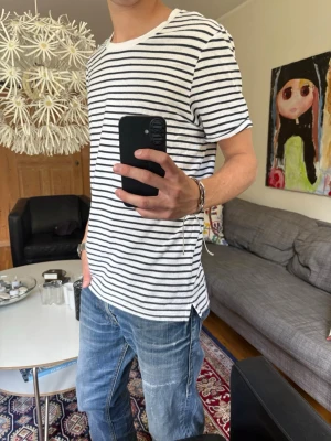 Randig vit och blå t-shirt - Säljer en klassisk vit t-shirt med blå horisontella ränder. Perfekt inför sommarn!