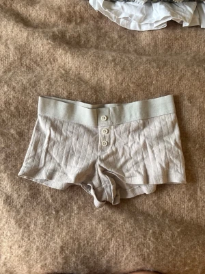rosa ribbade shorts med knappar - rosa shorts i ribbad bomull med bred resår i midjan och tre knappar framtill. De har ett randigt mönster och är mjuka och stretchiga för en bekväm känsla. Perfekta för sommarens chill dagar.