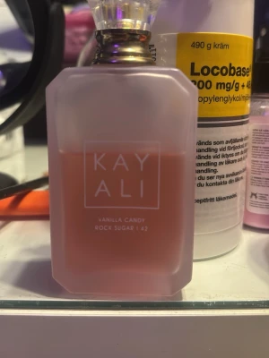 Kayali Vanilla Candy Rock Sugar 42 - (Pris kan diskuteras)Kayali Vanilla Candy Rock Sugar 42 är en parfym med söt och vaniljig doft. Flaskan är matt rosa med en elegant, multifasetterad form och har ett genomskinligt lock med gulddetaljer. Perfekt för dig som gillar söta och lekfulla dofter.