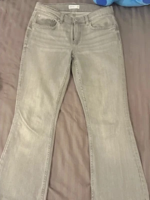 Grå bootcut jeans från Gina Tricot - Säljer ett par snygga grå bootcut jeans från Gina Tricot. Jeansen har klassisk femficksdesign, normal midja och utsvängda ben. Perfekta för dig som gillar en trendig och avslappnad stil. Materialet är mjukt denim med lite stretch för extra komfort.