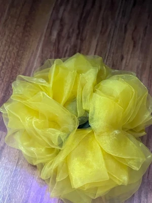 Gul hårklämma med organzablad - Snygg hårklämma med stora, fluffiga blad i gul organza. Klämman har en svart bas och ger ett riktigt statement till din frisyr. Perfekt för dig som vill sticka ut med en färgglad och trendig accessoar.