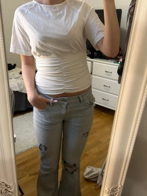 Snygg topp! - Trendig vit t-shirt med korta ärmar och croppad passform. T-shirten har snygga rynkade detaljer över magen 