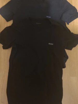 Svarta och mörkgrå BOSS t-shirts - Två stilrena t-shirts från BOSS i svart och mörkgrått med diskret logga på bröstet. Klassisk passform och korta ärmar, perfekta till jeans eller shorts. Materialet känns mjukt och bekvämt mot huden. Säljer för 199kr priset inte hugget i sten!