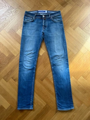 Jacob Cohën jeans - Snygga blå jeans från Jacob Cohën med klassisk femficksdesign och raka ben. Storleken (31) motsvarar ungefär W29 L32 då Italiens storlekar skiljer sig lite ifrån de svenska. Modellen heter Nick. Mycket bra skick - hör av dig vid minsta fundering!