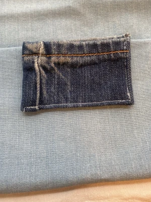 Liten korthållare i denimtyg - En liten rektangulär plånbok sydd av mörkblått denimtyg med synliga orange sömmar. Perfekt som accessoar. Enkel och stilren design utan synligt märke.