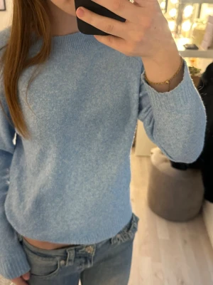 Ljusblå stickad tröja - Mysig ljusblå stickad tröja med rund halsringning och långa ärmar. Tröjan har en enkel, klassisk design och är perfekt att matcha med jeans. Materialet känns mjukt och passar bra för kyligare dagar.